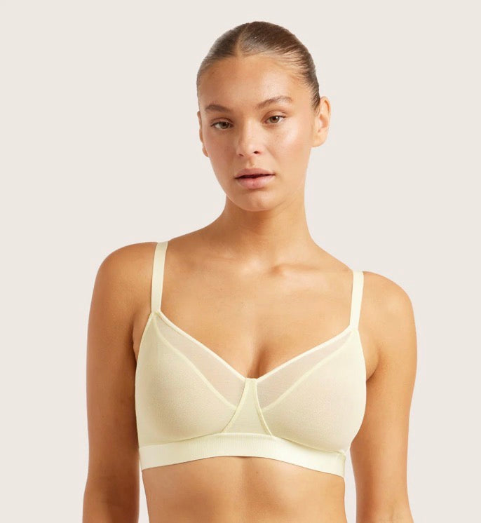 Woman wearing a lemon color bra against a plain background