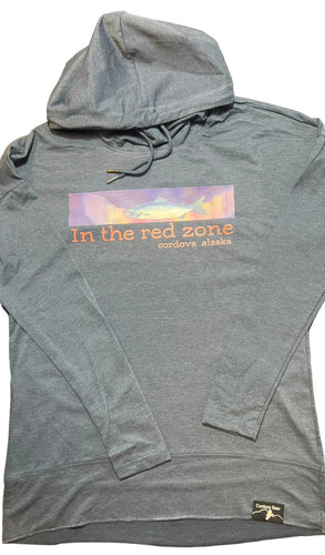 Blue hoodie with a fish, northern lights and “in the red zone, Cordova, Alaska” text on a washed indigo surface
