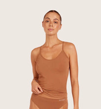 Woman wearing a maple brown cami tank top on a light beige background